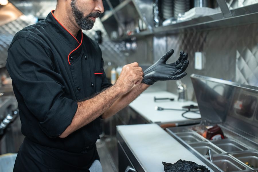 Chef enfilant des gants d'hygiène en cuisine professionnelle